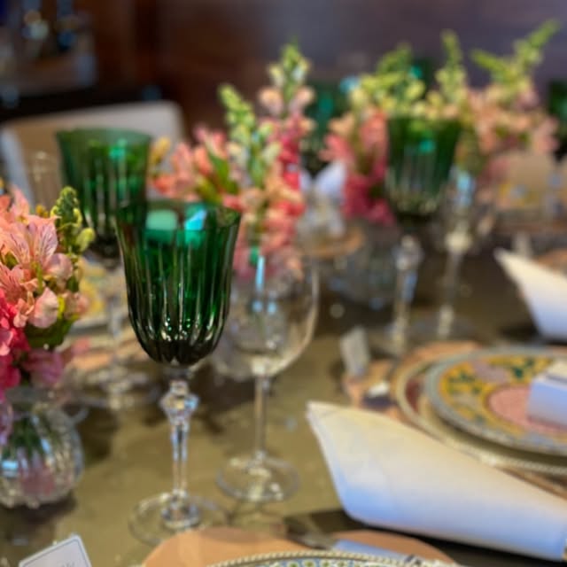 Mesa posta com taças verdes de cristal e flores